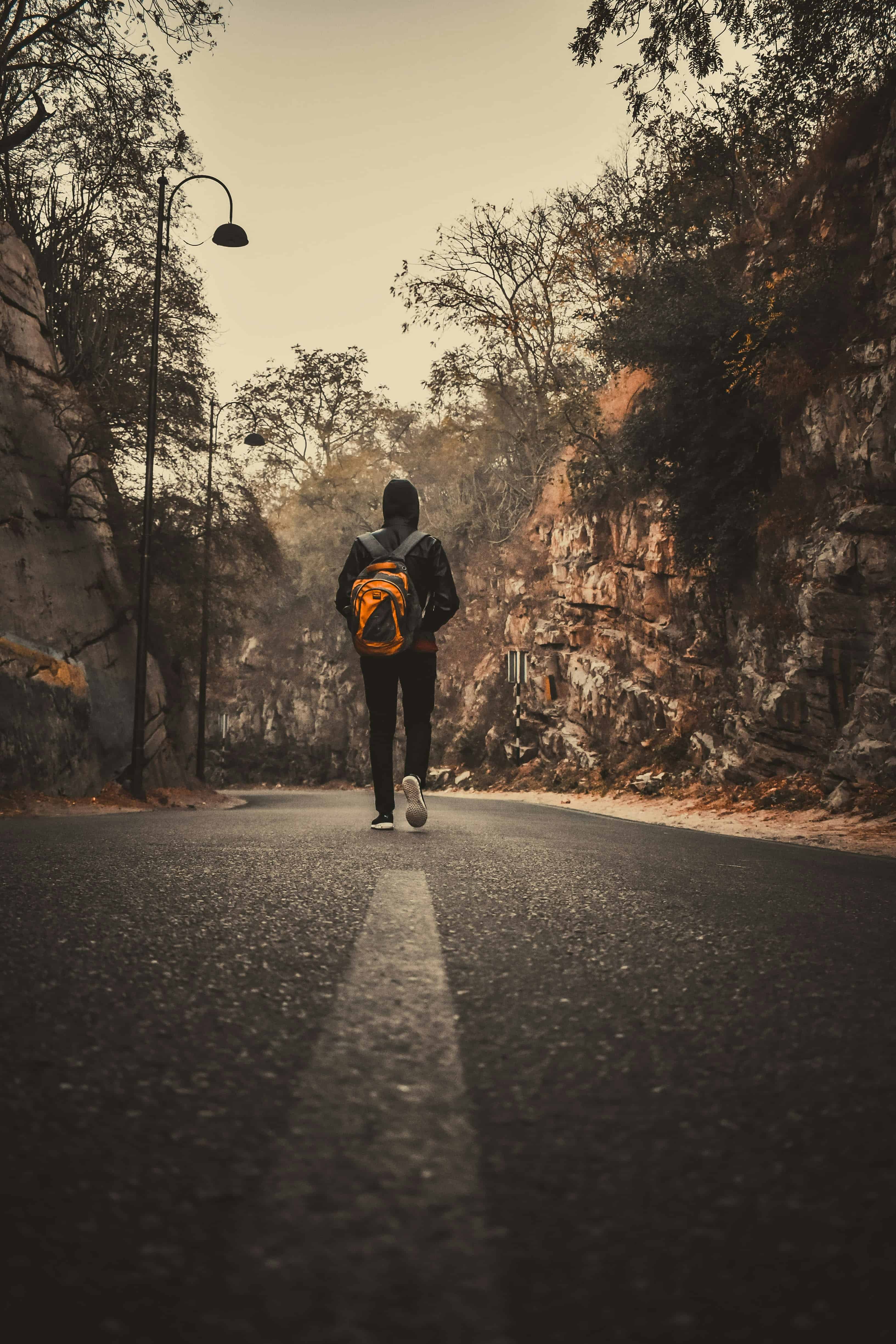 man in black jacket and black pants walking on road during daytime